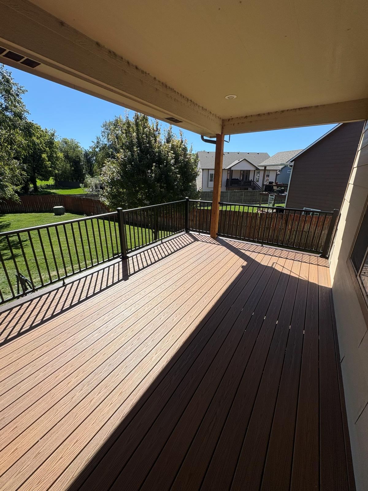 Covered composite deck looking out over the railing to the back yard