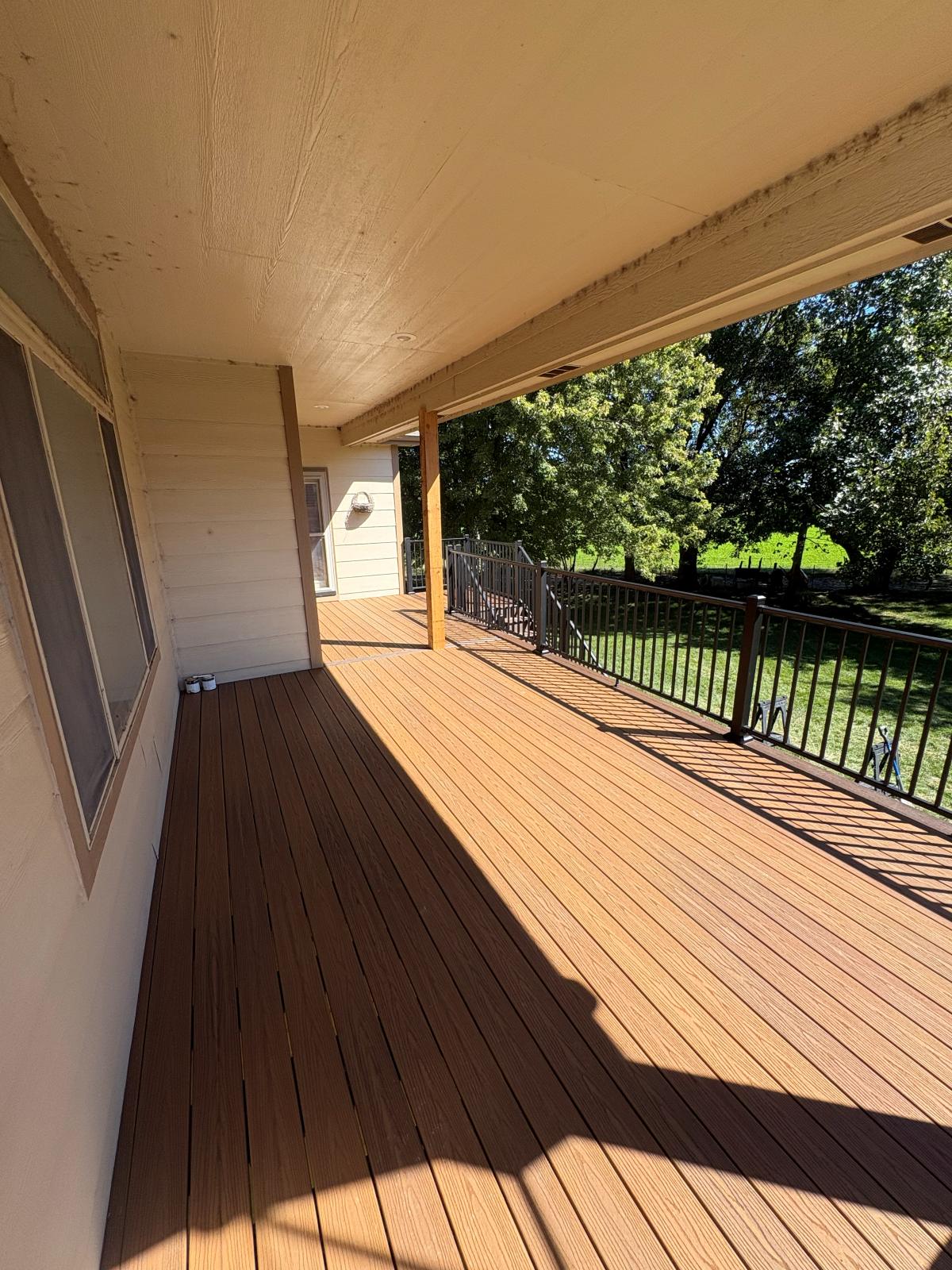 Covered end of a composite deck with two-tone decking and metal railing