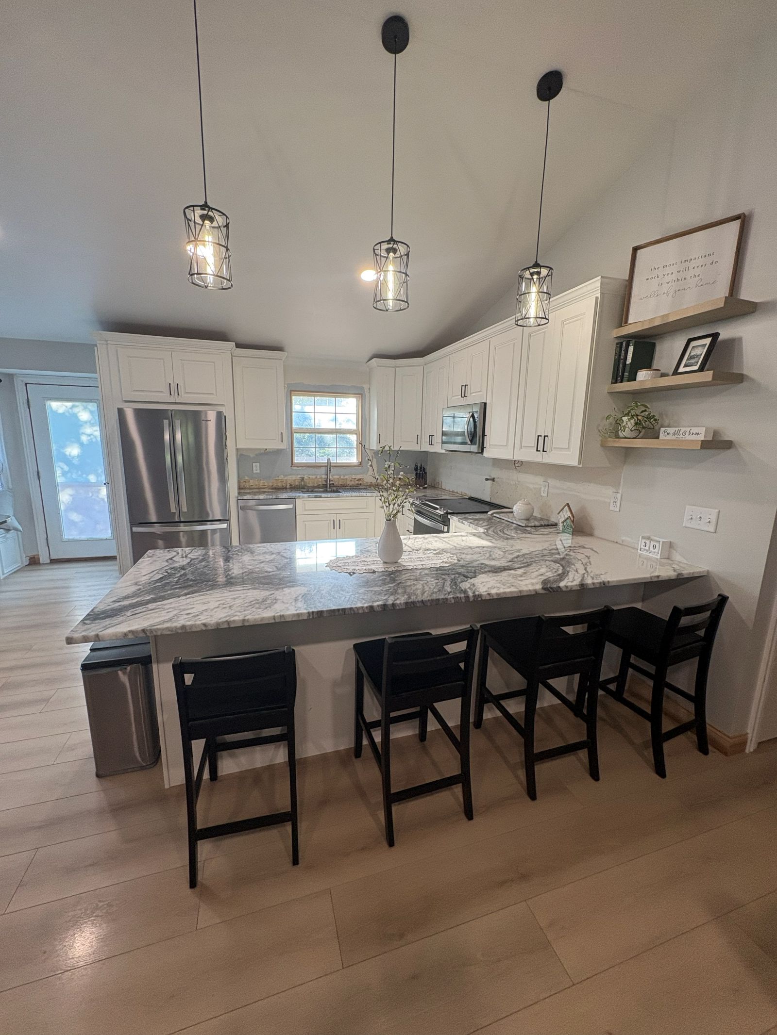 Remodeled kitchen with a granite peninsula, bar seating and pendant lighting