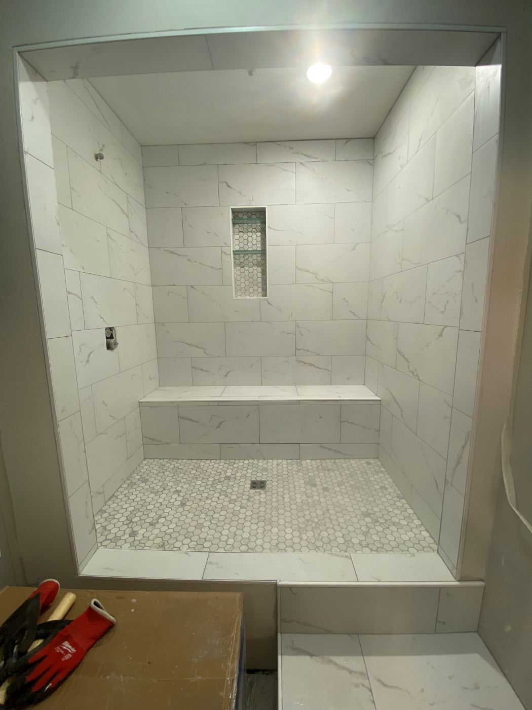Custom tile shower with a built-in bench and hex mosaic pan