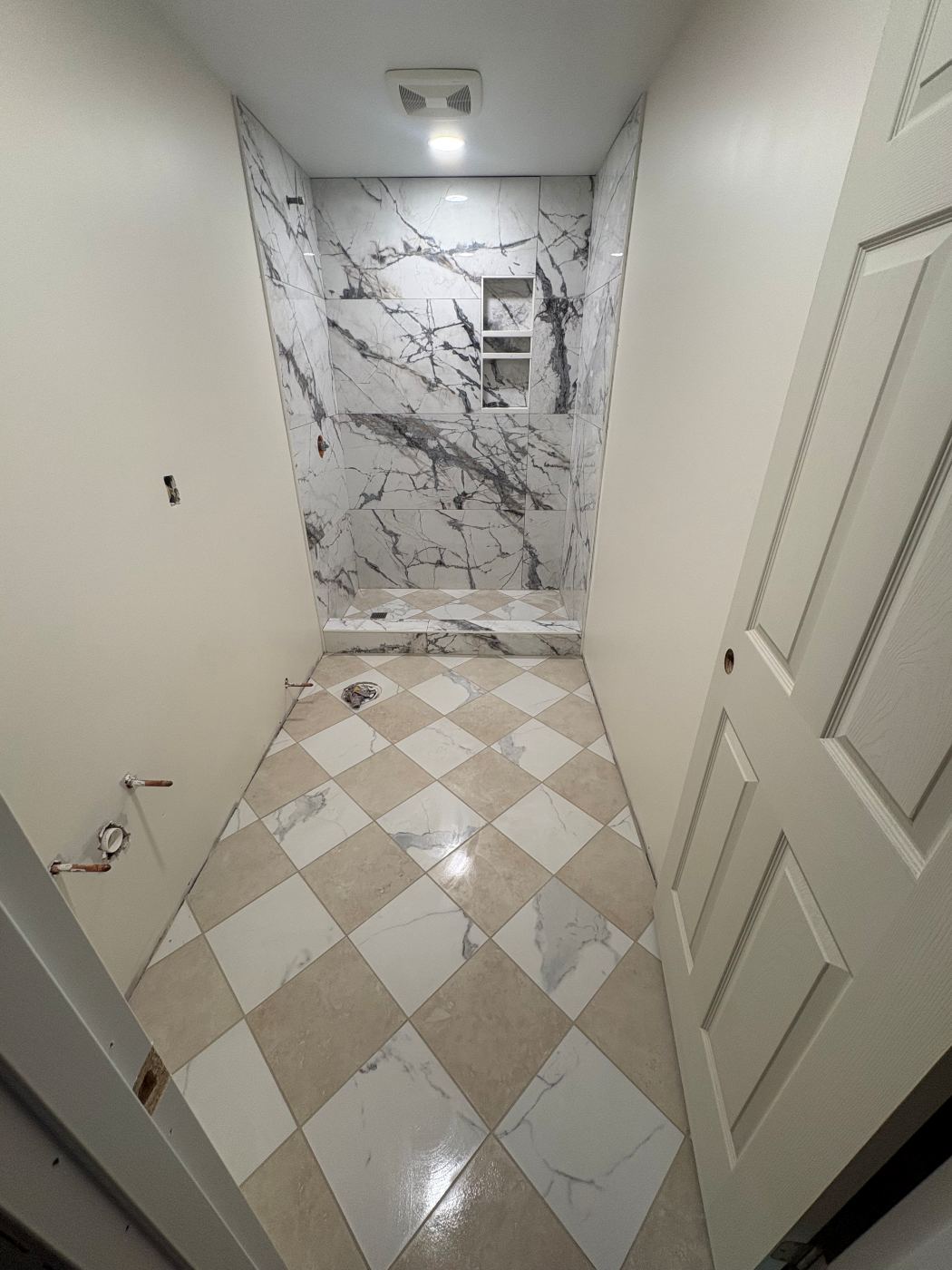 Marble-look tile shower with a diagonal checkerboard tile floor